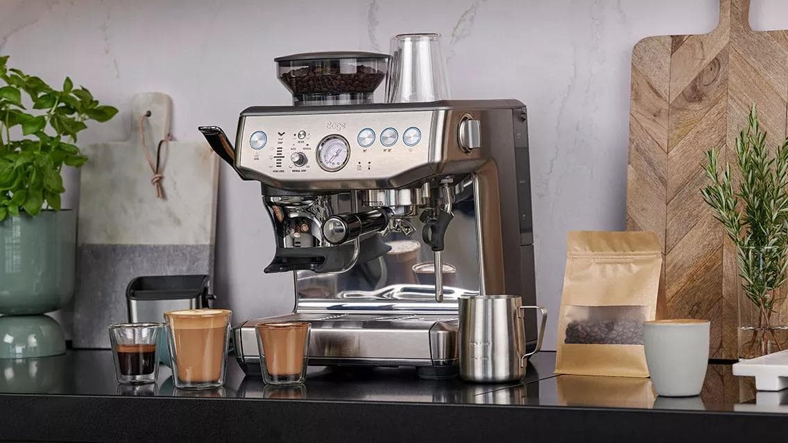 Sage Express Impress espressomachine op een keukenblad met espresso, melkdranken en koffiebonen ernaast